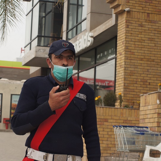 A Veteran Security & Protection (Pvt) Ltd, security guard holding a wireless set performing his duty outside a building.
